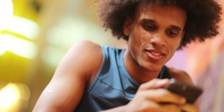 年轻英俊的非洲黑人男子手持手机科技设备微笑