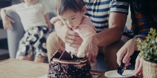 亚洲父亲抱着女儿切生日蛋糕(慢镜头)