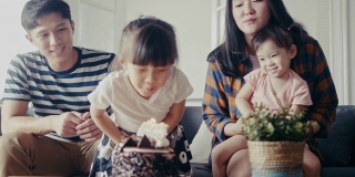 亚洲家庭在客厅为小女儿庆祝生日(慢镜头)