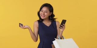 亚洲女人提着包，用信用卡在网上购物