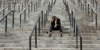 一个沮丧的商人坐在商业中心附近的楼梯上