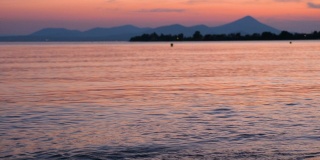 美丽的海景与在粉红色日落的山的景色。地中海上美丽的日落。水疗法的背景。自然海景。海岸线在日落。傍晚海面平静