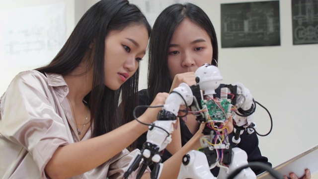 亚洲女工程师在实验室组装和测试机器人反应。建筑师设计电路会议分享技术思想和协作开发机器人。