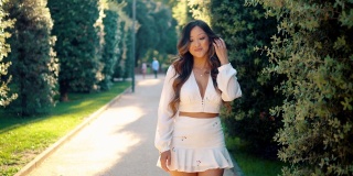美丽的亚洲女孩穿着白色的裙子在公园微笑