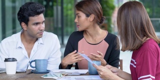 4K Medium拍摄的是年轻的成年亚洲商人和自由职业女商人在户外咖啡店一起使用数字平板电脑讨论业务。团队合作年轻的商人和女商人一起工作。