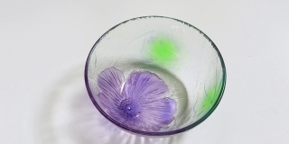 水倒进一个开着紫色花朵的玻璃碗里。