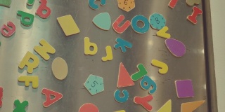 冰箱门上彩色磁铁的细节。由父母制作，儿子在家玩，家庭物品的概念