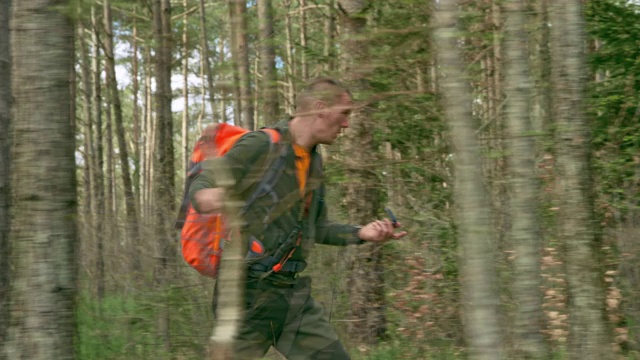 男性野外生存专家使用指南针在树林中行走