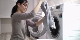 年轻的亚洲妇女在家里洗衣服