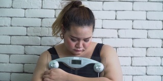 体型大的亚洲女人悲伤与体重秤