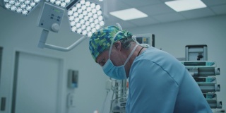 成熟的男性外科医生在ICU照明下手术