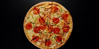 一个大披萨的圆圈在一个黑色的表面上旋转