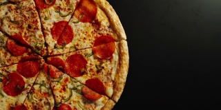 完整的披萨在左边的一个黑色表面上旋转