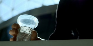一个残疾人拿着一个塑料杯子喝水。一只义肢举起一杯水。独立完整的生活与假肢。底视图