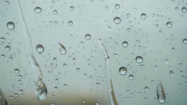 雨点落在窗外的玻璃上。关闭了。缓慢的运动。雨落在玻璃上。雨滴落在车窗背景上。秋天天气不好。