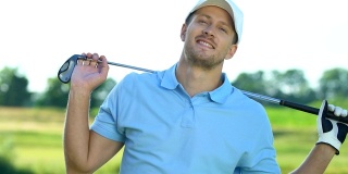 英俊的高尔夫球手在职业制服微笑相机与俱乐部摆姿势