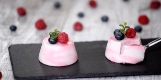美味的浆果慕斯甜点装饰新鲜的树莓，蓝莓和薄荷。
