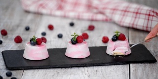 美味的浆果慕斯甜点装饰新鲜的树莓，蓝莓和薄荷。