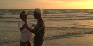 亚洲夫妇老年人退休休息放松跳舞日落海滩蜜月家庭一起幸福的人生活方式，慢镜头