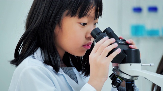 理科学生在学校实验室里看显微镜。教师和好奇的学生在教室实验室进行科学实验。教育、技术、团队、科学、人本理念。教育的主题