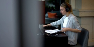 聪明的女企业家在电子耳机噪音消除检查信息从纸报告