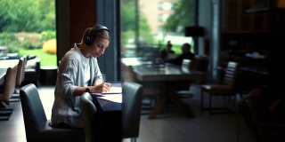 白人女性经济学家在耳机中听音乐通过耳机在工作过程中的财务报告