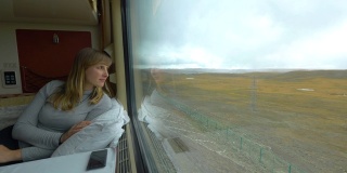 特写:微笑的旅客透过夜间火车的窗口望着平原
