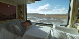 特写:疲惫的女孩睡在卧铺里，在火车穿越西藏的旅途中。