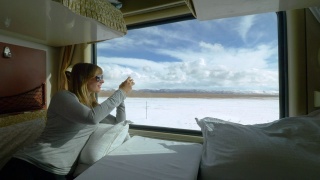 近距离观察:一名女子在火车上拍摄西藏雪景。视频素材模板下载