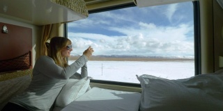 近距离观察:一名女子在火车上拍摄西藏雪景。