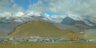 在西藏平原的村庄后面，有雪景如画的喜马拉雅