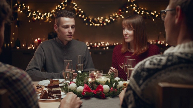 朋友庆祝圣诞节。他们坐在圣诞餐桌前，在一个舒适的家庭环境中交流。