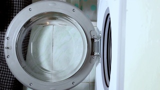 男人的手把要洗的衣服放进洗衣机。视频素材模板下载