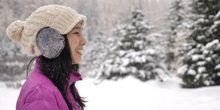 亚洲女人在冬天的森林里享受雪