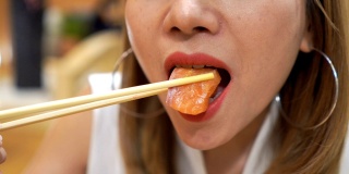 近距离观察日本妇女吃鲑鱼生鱼片生食物的嘴