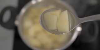 用汤勺将煮熟的土豆切片，放在土豆锅的背景上。4 k。4 k的视频