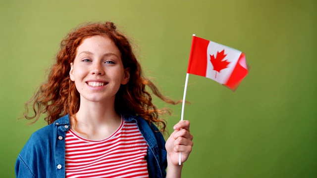 美丽的女孩举着加拿大国旗站在绿色的背景