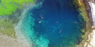 Top view of a clear cold blue lake. Divers in suits swim in clear, clear water. Water with blue minerals aerial view.