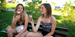 两个女人坐在那里舔着巧克力和香草冰淇淋