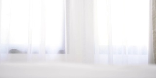 白色的室内，白色背景的窗帘和床上用品的窗户