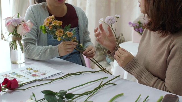 年轻的花商正在训练她的朋友如何做花束