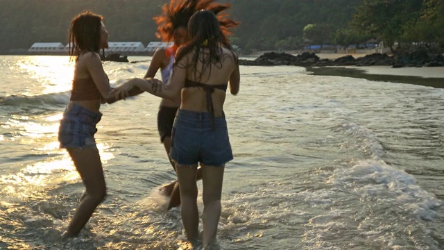 在阳光明媚的早晨，穿着比基尼的妇女们沿着海滩和大海跳舞。