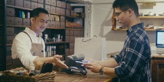 亚洲男人在男士精品店用手机付款(慢镜头)