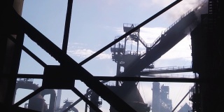 老工厂的烟囱在蓝色的天空中翻腾着灰白色的烟柱。透过窗户观看。框架