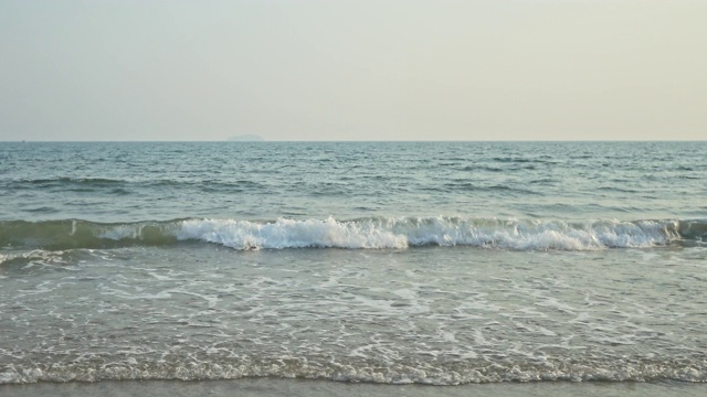 在阳光明媚的早晨，年轻的女子拿着冲浪板在海滩上与大海散步。