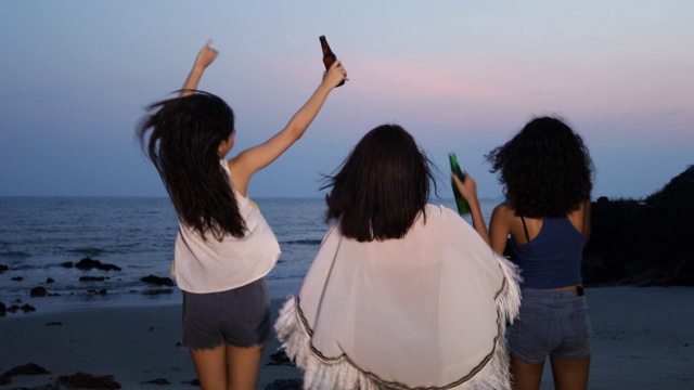 快乐的女性朋友群喝啤酒在海滩，友谊的概念与年轻的女性朋友享受时间和有真正的乐趣在露营