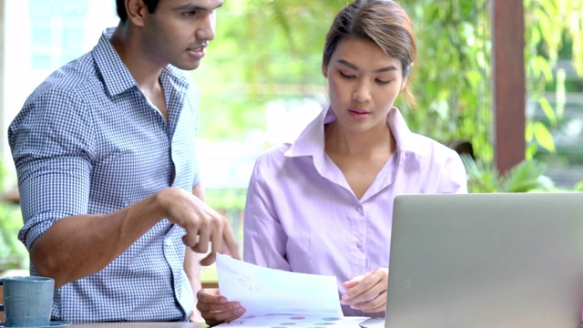 4K Medium拍摄亚洲商人和女商人在户外咖啡厅使用笔记本电脑和互联网谈论和分享金融业务的想法。户外办公理念。