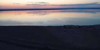 日落时分，汽车在沙漠中间的空旷道路上行驶的鸟瞰图