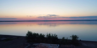 鸟瞰蒙古包，船只和人们在日落时游泳在一个湖泊，中国新疆