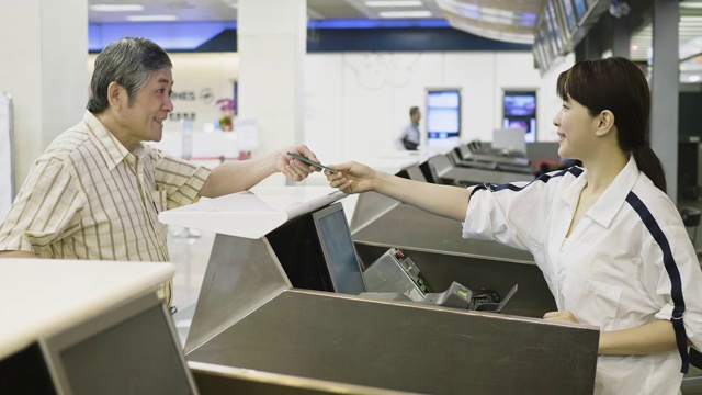 亚洲资深男子向航空公司登记服务员出示护照